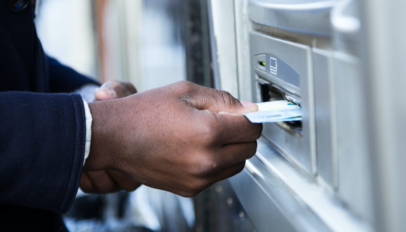 Close up of man taking cash from ATM with credit card.