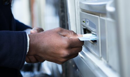 Close up of man taking cash from ATM with credit card.