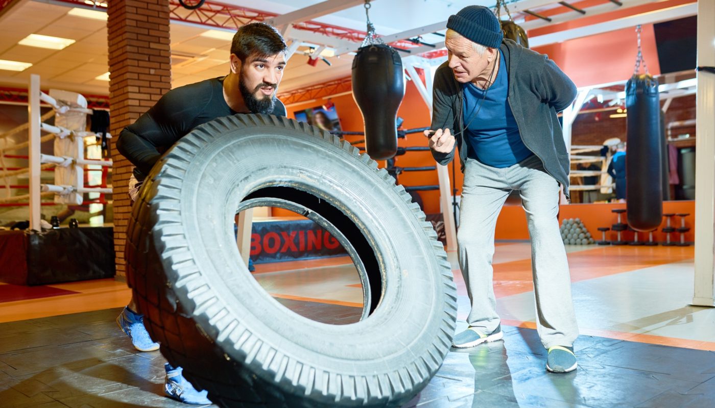 Sportsman flipping tire with coach near