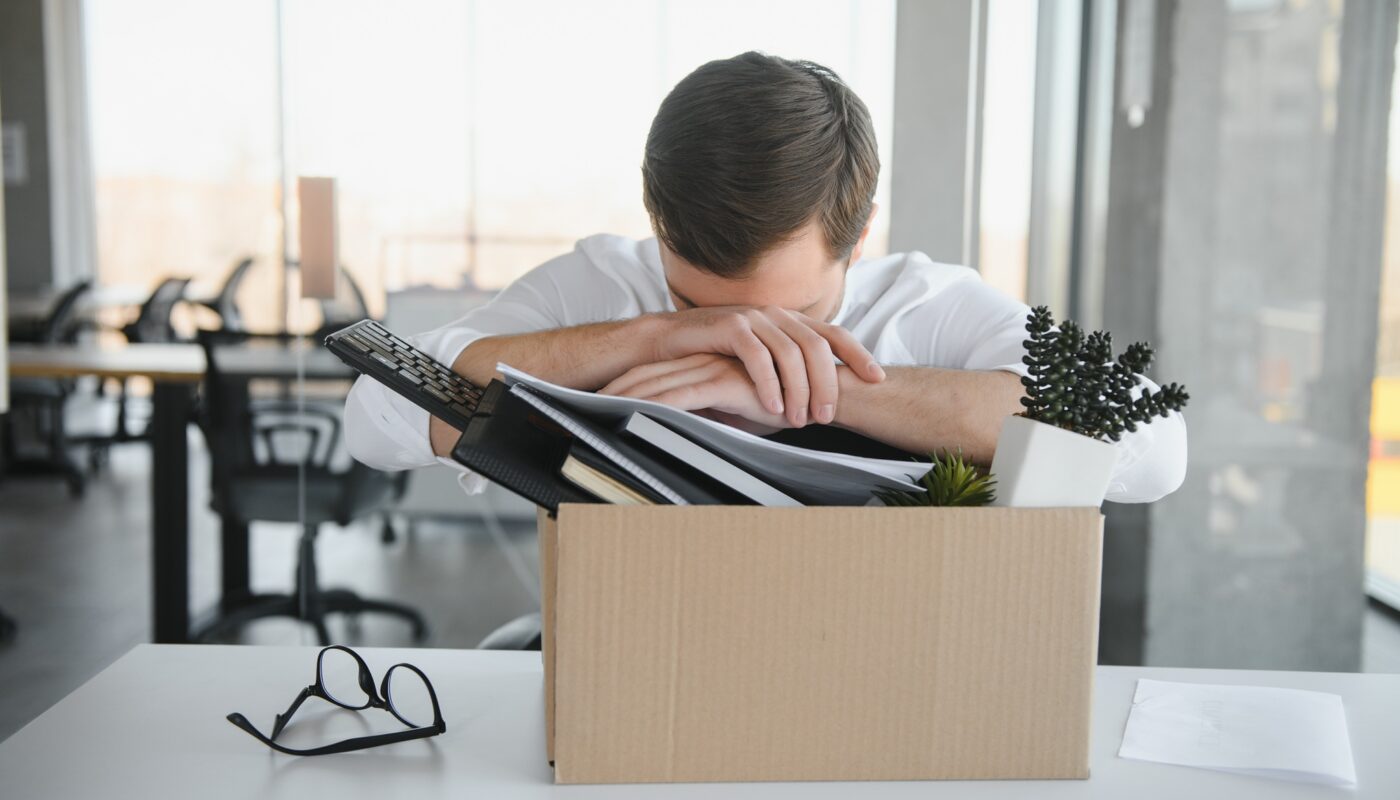 business, firing and job loss concept - fired male office worker with box of his personal stuff.